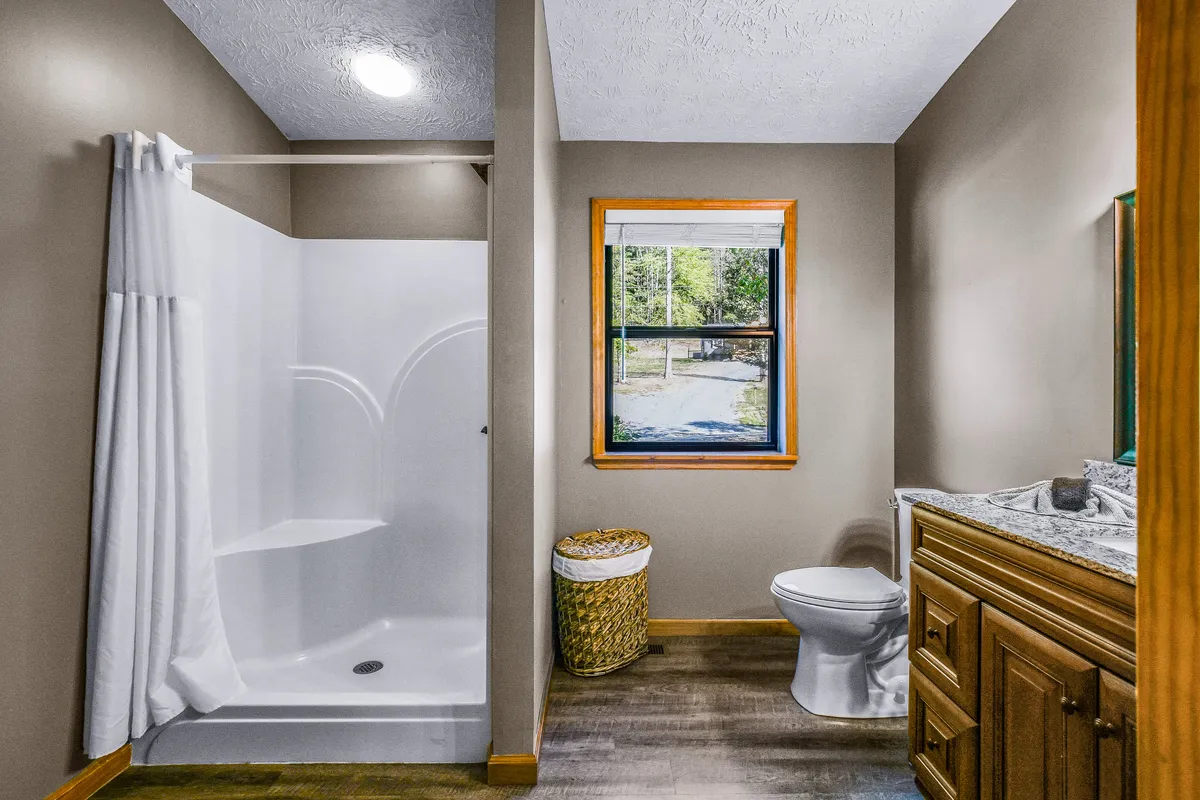 A bright, serene bathroom with a walk-in shower, vanity, toilet, and soft natural light streaming through a window. Clever storage and a calm, spa-like atmosphere invite relaxation.