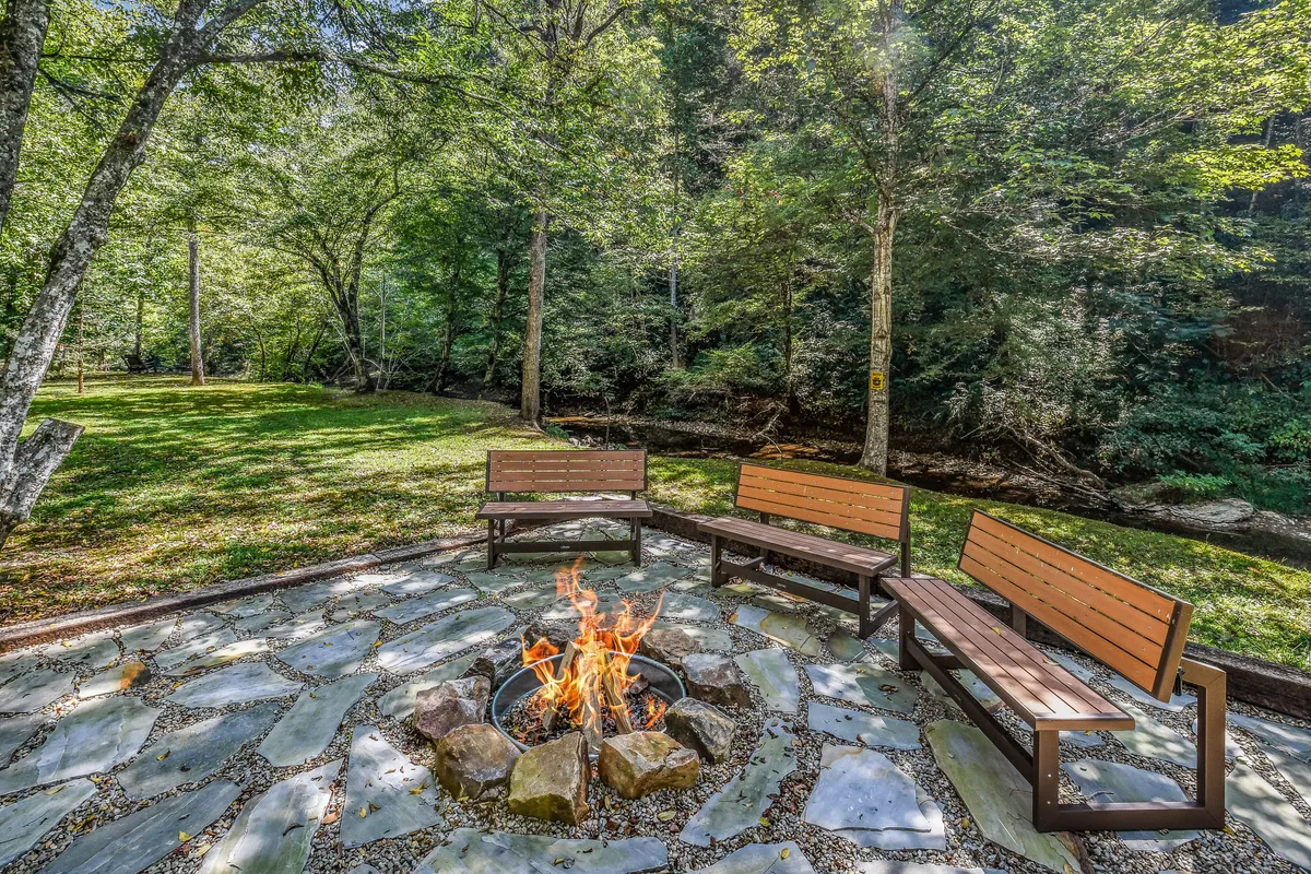 A cozy fire pit area nestled in a natural landscape, with surrounding seating perfect for group gatherings. The setting is tranquil yet social, ideal for storytelling, roasting marshmallows, or stargazing after a day of adventure.
